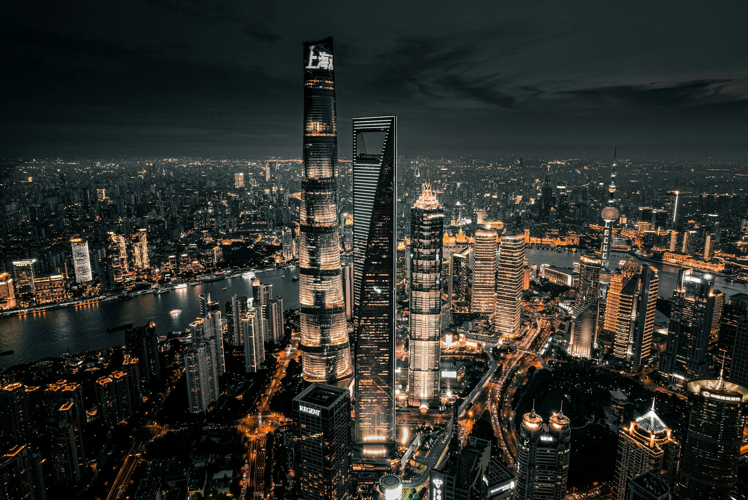 Shanghai's Pudong skyline at night, with neon reflections on the Huangpu river.
