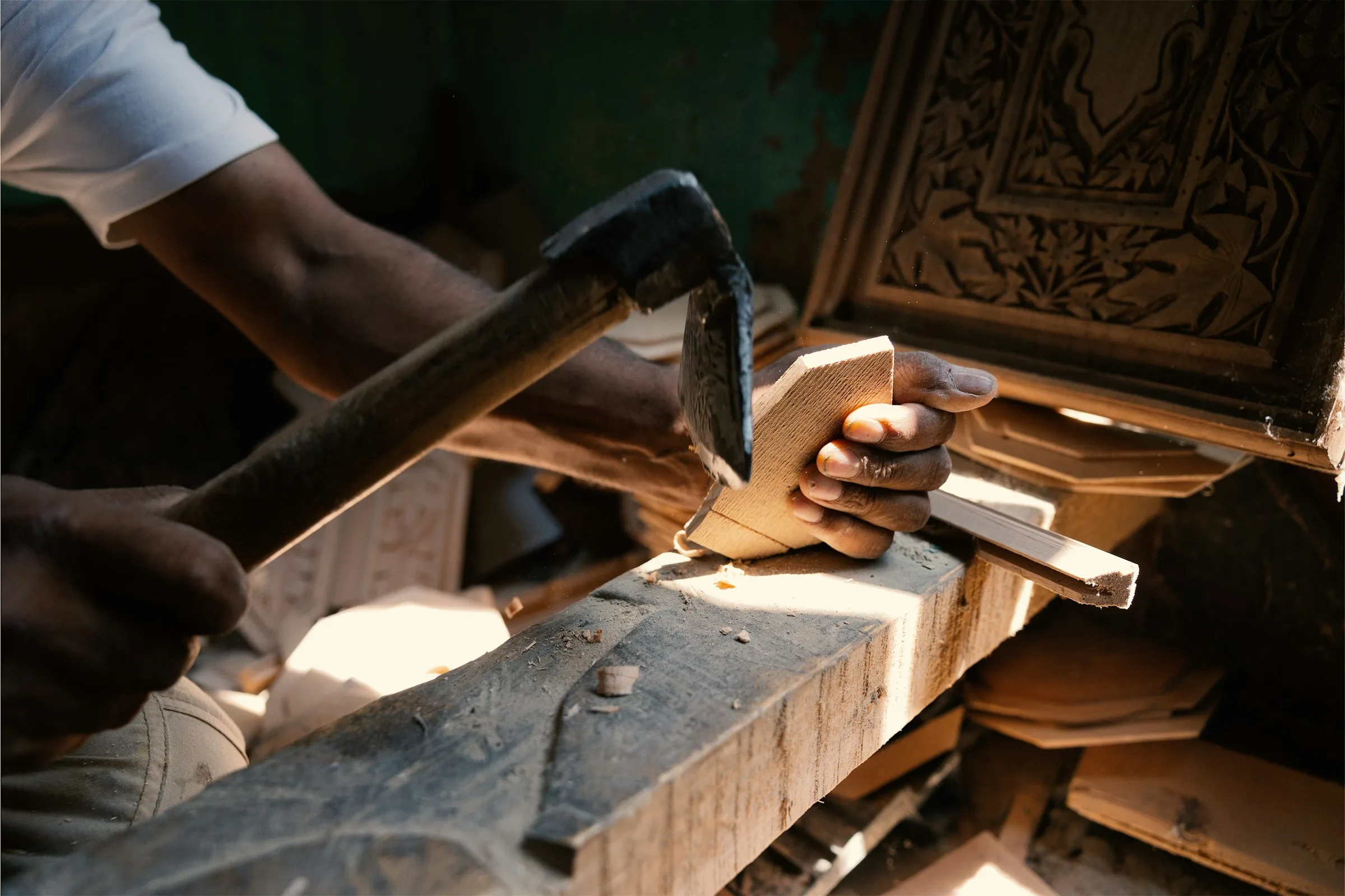 Hands working on a piece of wood at a carpenter's bench — bespoke craftsmanship in close-up.
